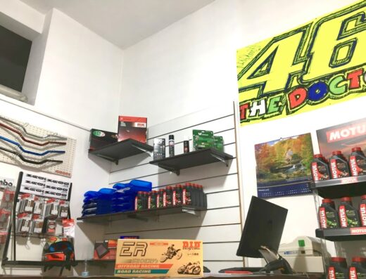 Interno del GP Store a Procida: esposizione di manubri moto, accessori, ricambi come olio Motul, caschi e prodotti per la manutenzione. Poster del numero 46 di Valentino Rossi.