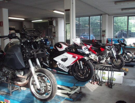 GPM Moto di Panzeri Giovanni Battista: Diverse motociclette in riparazione su piattaforme elevatrici all'interno dell'officina.