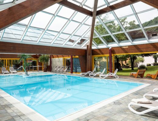 Piscina coperta e scoperta del Grand Hotel Gortani a Borgo Gortani, con lettini prendisole interni ed esterni per il relax degli ospiti.