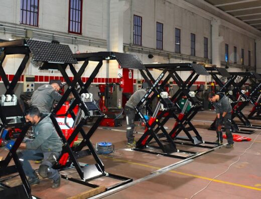 Installazione di ponti sollevatori per auto in un'officina meccanica da parte di operai specializzati. Attrezzature per gommisti e officine.