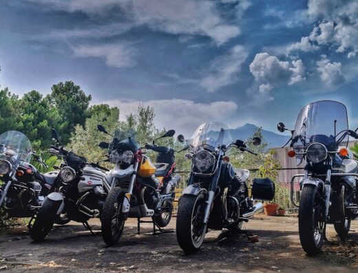 Guzzisti dell'Etna Moto Guzzi Club mostra una fila di moto Guzzi parcheggiate con l'Etna sullo sfondo, ideali per viaggi e accessori moto