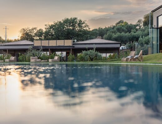 Hang Loose Cottage resort in Gizzeria, Calabria, featuring a tranquil pool reflecting the hotel's architecture and a serene sunset backdrop.
