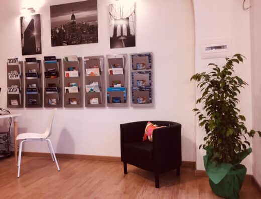 Interno di Happy Travel di Giusi Furci, con arredamento moderno, brochure di viaggi, sedie e pianta ornamentale.