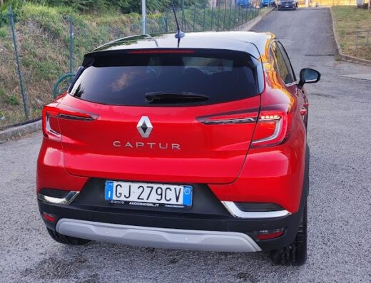Vista posteriore di una Renault Captur rossa parcheggiata su una strada asfaltata, ideale per il lavaggio self-service presso Happy Wash.