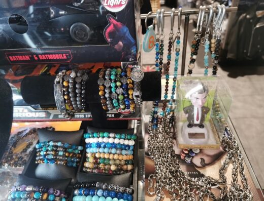 Display of beaded bracelets, necklaces, and a Batman Batmobile toy car at a market stall, showcasing accessories for motorcycle enthusiasts and collectors.
