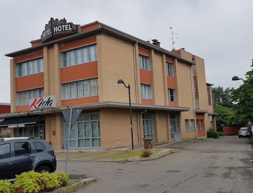 Esterno dell'Hotel Alba, una struttura a più piani con insegna "Hotel" sul tetto e un cartello "Kida Ristorante Pizzeria" all'ingresso. Un'auto è parcheggiata di fronte.