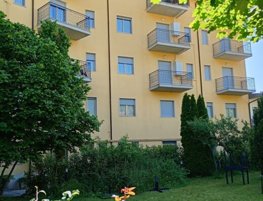 Hotel Aquila con facciata gialla e balconi, circondato da vegetazione. Servizio di noleggio e-bike disponibile per esplorare la zona.