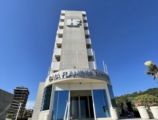 Hotel Baia Flaminia Resort: vista esterna dell'edificio con insegna e gradinata d'ingresso, ideale per vacanze e viaggi in Italia.