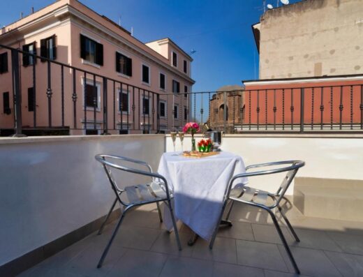 Tavolo apparecchiato con fiori e champagne sul balcone dell'Hotel Balilla, per un soggiorno romantico a Roma.