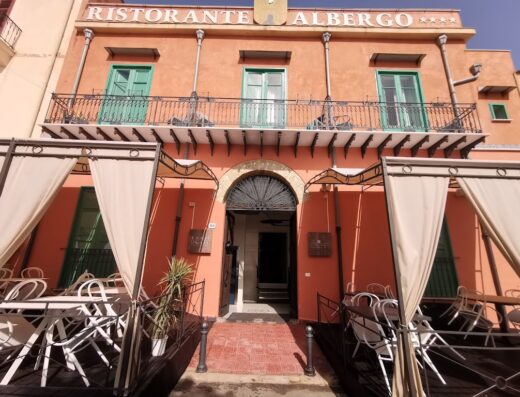 Facciata dell'Hotel Borgo di Ciàula, un ristorante-albergo a quattro stelle con balconi in ferro battuto e tavoli all'aperto.