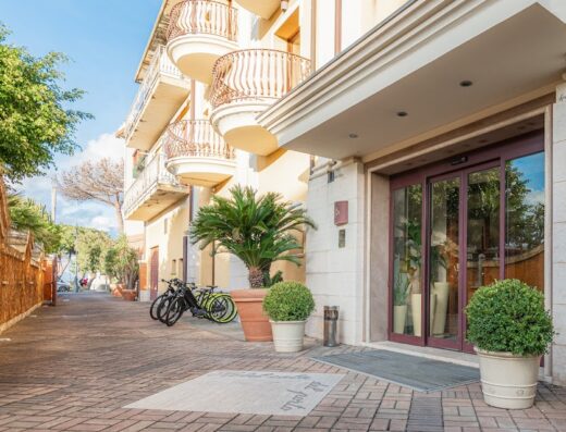 Hotel Cala del Porto entrance in Italy with two bicycles parked outside, showcasing travel and accommodation services.
