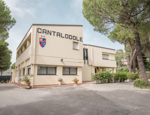 Foto dell'Hotel Cantalodole, una struttura a due piani con il nome e il logo ben visibili sulla facciata principale, circondata da alberi.