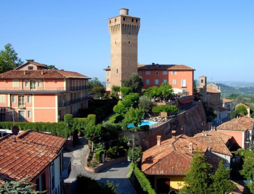 Hotel Castello di Santa Vittoria in Santa Vittoria d’Alba, Italy, featuring the castle tower, hotel buildings, swimming pool, and surrounding landscape.