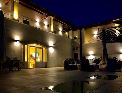 Hotel Cave Del Sole Resort & Beauty outdoor courtyard at night, featuring comfortable seating, ambient lighting, and reflective water features, creating a relaxing atmosphere.