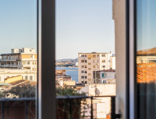 Vista dalla finestra dell'Hotel Centrale, con edifici cittadini, tetti rossi e il mare sullo sfondo, che offre uno scorcio del panorama urbano.