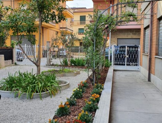 Hotel Cormorano: giardino curato con fiori colorati e alberi tra gli edifici residenziali, un'oasi di verde per un soggiorno rilassante.
