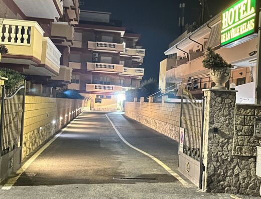 Ingresso illuminato dell'Hotel De La Ville Relais di notte, con cancello in ferro e insegna luminosa ben visibile