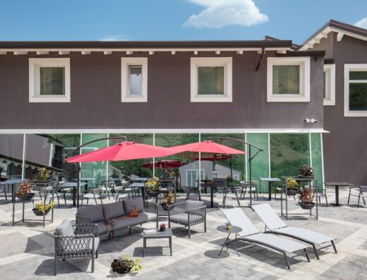 Hotel Della Piana: Elegante area relax esterna con divani, lettini prendisole e ombrelloni rossi per un soggiorno confortevole.