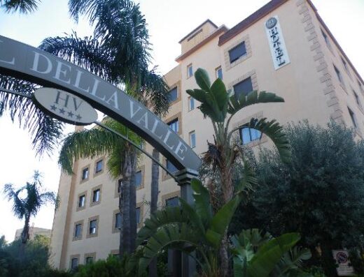 Esterno dell'Hotel della Valle, una struttura a quattro stelle con vegetazione tropicale, ideale per un soggiorno rilassante e confortevole.