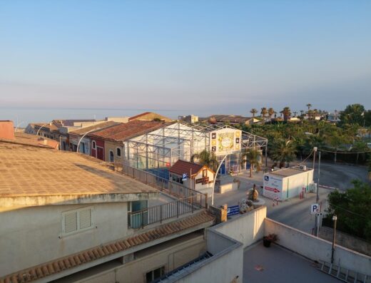 Vista panoramica di Hotel Don Giovanni 1943, con architettura locale, vegetazione mediterranea e scorcio sul mare all'orizzonte.