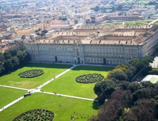 Vista aerea della Reggia di Caserta, un grande palazzo storico con giardini curati, ideale per un soggiorno culturale vicino all'Hotel Europa Art Caserta.