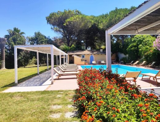 Hotel Is Benas Country Lodge: Vista della piscina con lettini e fiori rossi, che offre un'oasi di relax e comfort.