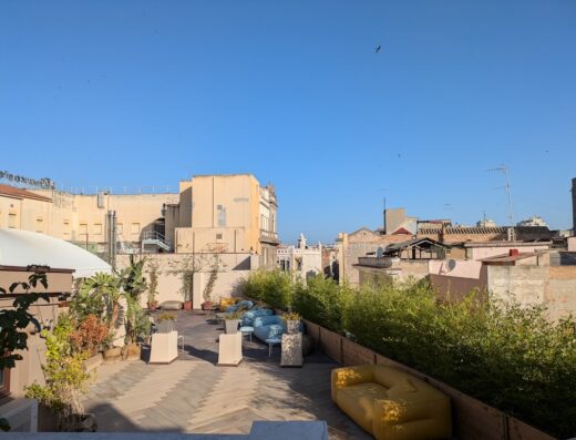 Terrazza panoramica dell'Hotel Italia con pavimentazione in legno, divani colorati, piante e vista sulla città.