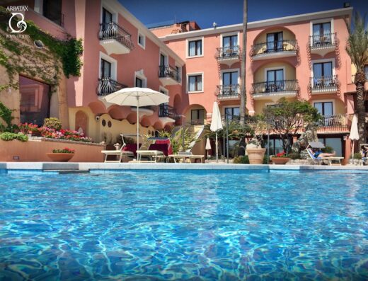 Hotel La Bitta vista piscina, Arbatax Park Resort. Architettura colorata, ombrelloni bianchi e acque cristalline per una vacanza di lusso.