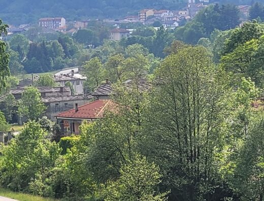 Vista panoramica di La Colletta, Italia, con case tradizionali, vegetazione lussureggiante e montagne sullo sfondo, ideale per viaggi e relax.