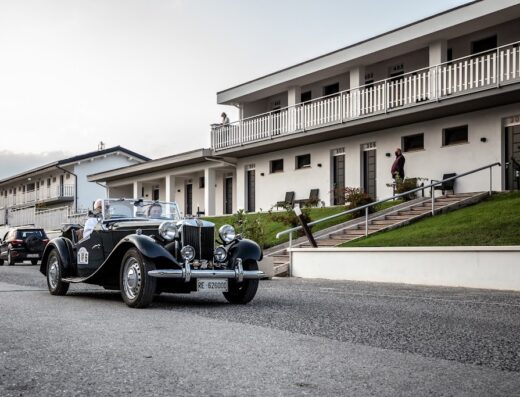 Auto d'epoca nera parcheggiata di fronte all'Hotel La Compagnia Del Viaggiatore con persone visibili, turismo su strada e viaggi
