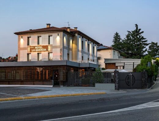 Hotel La Quercia, elegante struttura ricettiva con facciata moderna e insegna luminosa, situato in una tranquilla zona residenziale.