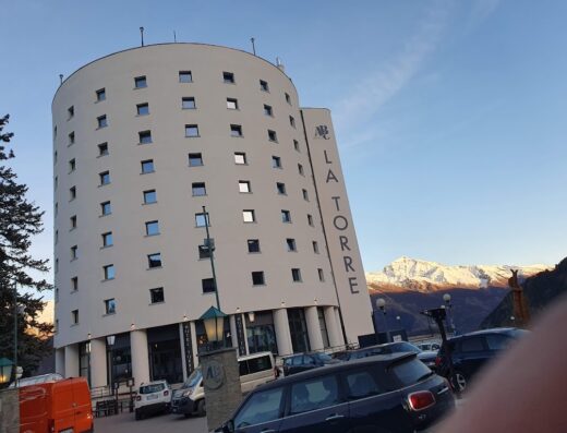 Hotel La Torre, una moderna struttura cilindrica con vista sulle montagne innevate, offre servizi di ospitalità e parcheggio.