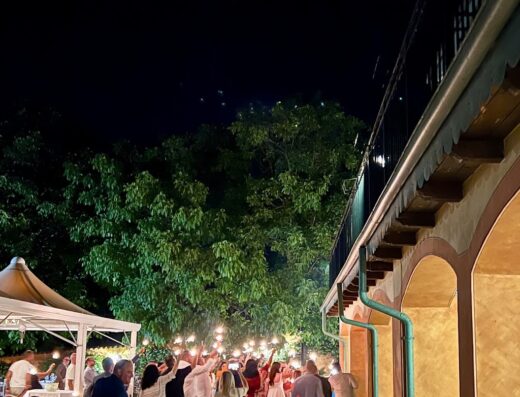 Serata di festa all'Hotel La Valle dell'Aquila: persone riunite all'aperto, tavoli imbanditi e atmosfera vivace, illuminata da luci soffuse e decorazioni.