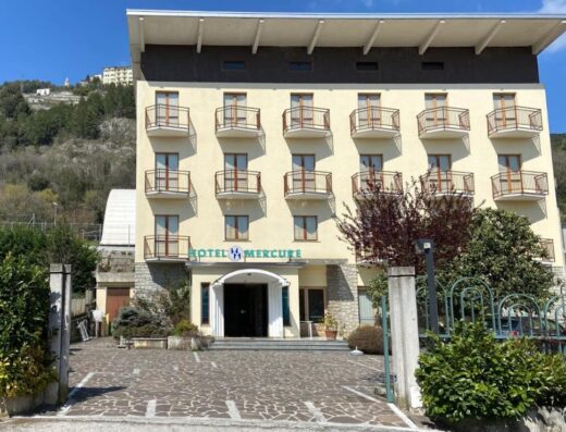 Facciata principale dell'Hotel Mercure Di Sproviero con balconi e ingresso ben visibile, situato in una zona collinare