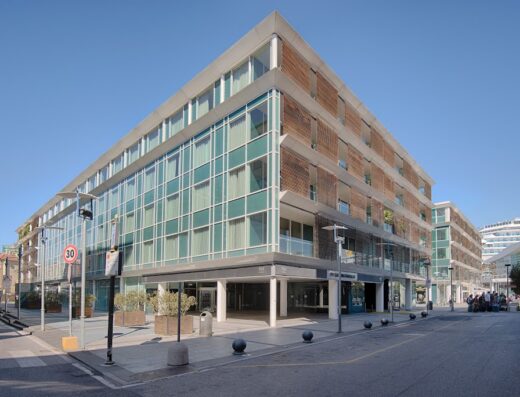 Hotel NH Savona Darsena: moderna facciata in vetro e legno con vista sul porto turistico e una nave da crociera sullo sfondo, situato in una zona urbana ben illuminata.