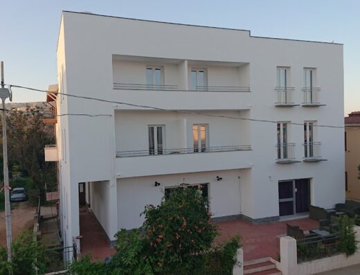 Hotel Ogliastra: Facciata esterna dell'hotel con balconi, terrazza con tavoli e sedie, e vista sul paesaggio circostante. Alloggi turistici a Ogliastra.