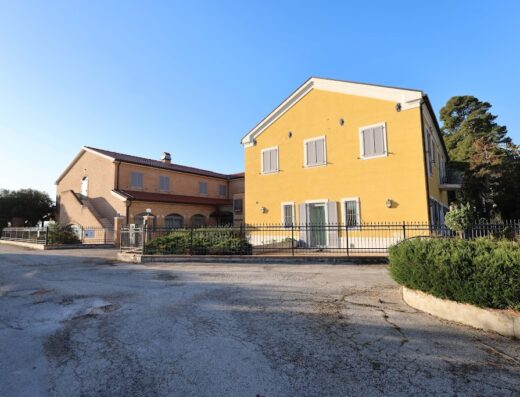 Hotel Palazzo Bello: Esterno dell'edificio principale con facciata gialla e struttura adiacente in mattoni, recinzione in ferro battuto e area parcheggio.