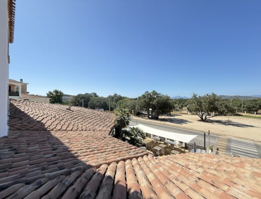Vista dal Hotel Poseidonia che mostra un tetto di tegole rosse, strada con strisce pedonali, alberi e cielo azzurro.