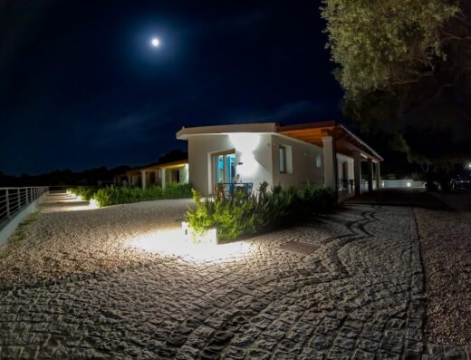 Hotel Pranos Turismo Rurale di notte, illuminato dalla luna, con vialetto in pietra e vegetazione curata, Sardegna.