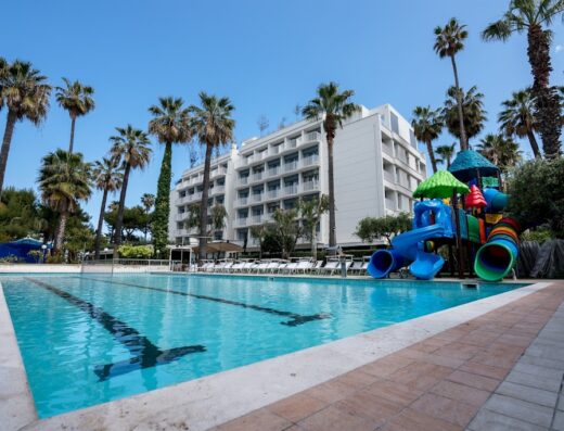 Hotel Relax: ampia piscina con acqua cristallina, scivoli colorati per bambini e palme tropicali per una vacanza rilassante.