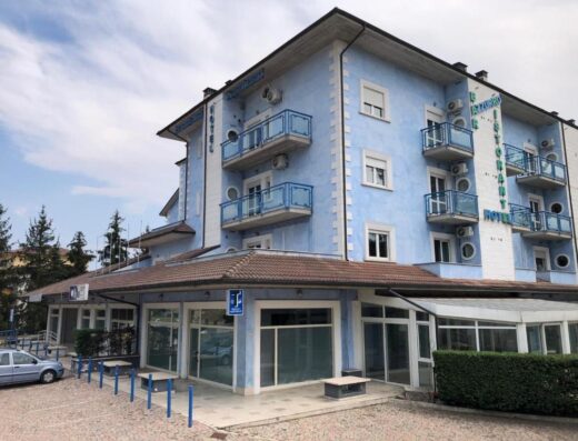 Hotel Residence Azzurro: Facciata esterna dell'hotel con balconi blu, insegna del ristorante e area parcheggio. Albergo a gestione familiare.