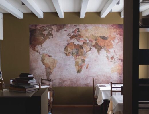 Interni del Hotel Ristorante Da Belie con una grande mappa del mondo sulla parete, tavoli apparecchiati e scaffali con bottiglie.