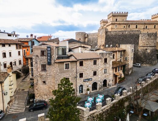 Hotel Ristorante Mastrodattia: Vista aerea del borgo medievale con il castello sullo sfondo, hotel con insegna e tavolini all'aperto, ideale per un soggiorno e una pausa culinaria.