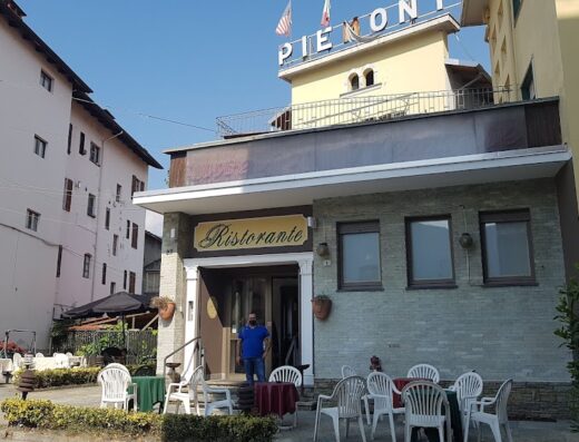 Foto dell'Hotel Ristorante Piemonte con tavoli all'aperto, insegna "Ristorante" ben visibile e facciata dell'hotel con bandiere.