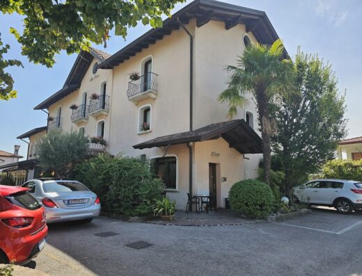 Hotel Ristorante Villa Monica, Italia: Vista esterna dell'hotel con balconi fioriti, auto parcheggiate e vegetazione rigogliosa per un soggiorno rilassante.
