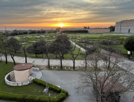 Alba suggestiva sulla Reggia di Caserta, con vista sui giardini reali, offrendo un'esperienza unica durante il soggiorno all'Hotel Royal Caserta.