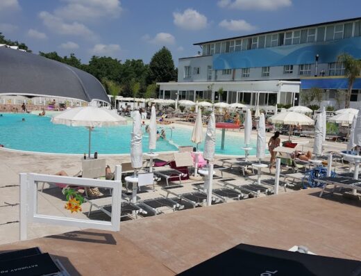 Vista della piscina all'Hotel Saturday, con ombrelloni, lettini e persone che si godono la giornata di sole. Relax e divertimento in un'oasi di vacanza.