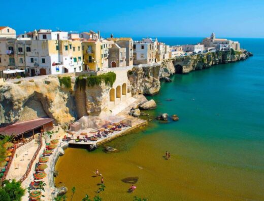 Vista aerea mozzafiato di Vieste, Italia, con le sue case bianche arroccate sulle scogliere a picco sul mare Adriatico cristallino. Spiaggia invitante e architettura storica.