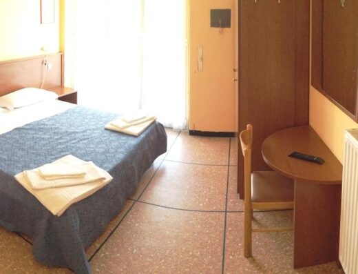 Camera accogliente dell'Hotel Suisse con letto matrimoniale, scrivania, sedia, radiatore e armadio a muro per un soggiorno confortevole.