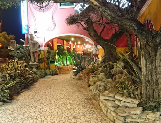 Ingresso dell'Hotel Tabina a Santa Maria di Sala, con decorazioni esterne, statue, piante e illuminazione notturna.